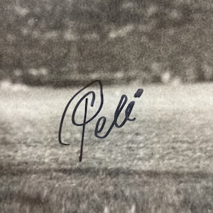 May include: Black and white photo of a soccer field with the signature "Pel&eacute;" written in black ink.