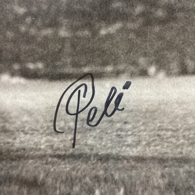 May include: Black and white photo of a soccer field with the signature "Pel&eacute;" written in black ink.