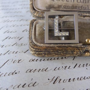 Lindo broche de cristal em pasta Art Déco dos anos 1920 com a letra L em configuração cromada