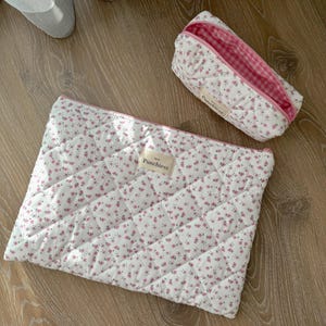 May include: Two quilted fabric pouches with pink floral patterns and pink and white gingham lining. The larger pouch has the word "Panchies" printed on it.