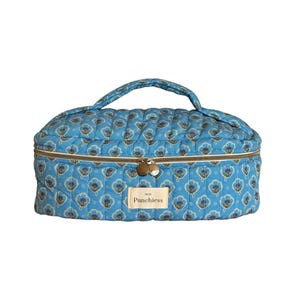 May include: A blue quilted makeup bag with a floral print and a gold zipper. The bag has a gold handle and a label that says "Punchies" on it.