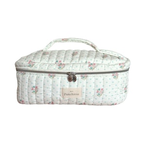 May include: A white quilted makeup bag with a floral print and a silver zipper. The bag has a handle and a label that says "Punchies" on it.