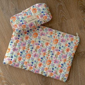 May include: Two quilted zippered pouches with a floral print in shades of pink, orange, blue, and green. The pouches have the text "Punchless" printed on them.