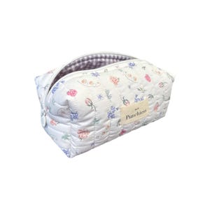 May include: White quilted makeup bag with a floral print and the text "So Much Punchierss" on the front.