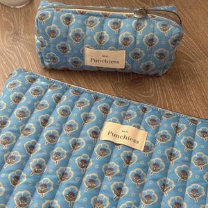 May include: A blue quilted makeup bag with a floral pattern and the text "Est. 21 Punchies" on the front.