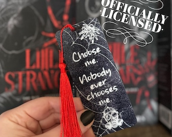 Puede incluir: Marcapáginas en blanco y negro con un diseño de telaraña y el texto "Choose me. Nobody ever chooses me." El marcapáginas tiene un borla roja.