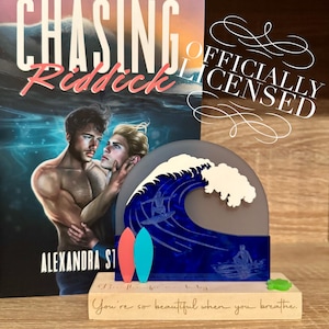 May include: A book cover titled "Chasing Riddick" and a decorative wave scene. The wave scene features two surfboards and the text "You're so beautiful when you breathe."