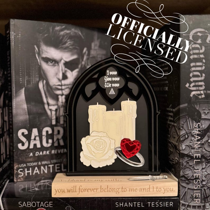 May include: A black gothic-style decorative piece with three cream-colored candles, a white rose, and a red heart-shaped gem ring. The text "I vow You vow We vow" is above the candles. The words "OFFICIALLY LICENSED" are also visible.