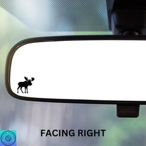 May include: A black silhouette of a moose facing right is visible in the reflection of a rearview mirror of a car. The text "FACING RIGHT" is below the mirror.