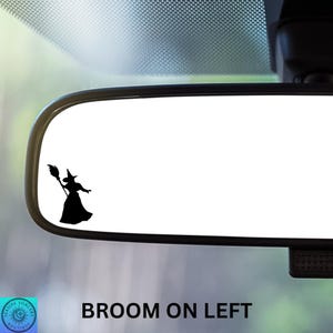 May include: A black silhouette of a witch with a broom is on the left side of a car's rearview mirror. The text "BROOM ON LEFT" is below the mirror. The image is a sticker or decal.