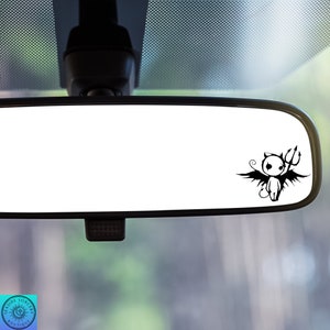 May include: A black and white car rearview mirror with a small black and white cartoon devil with wings and a trident.