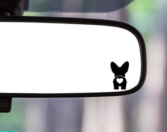 May include: Black vinyl car decal featuring a stylized silhouette of a dog's rear end with a heart-shaped design. The decal is placed on a car's rearview mirror, with the Seaside Sorcery Boutique logo visible.