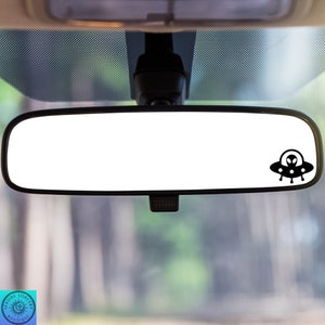 Peut inclure: Un autocollant de r&eacute;troviseur noir et blanc repr&eacute;sentant un OVNI avec un extraterrestre &agrave; l'int&eacute;rieur. L'autocollant est plac&eacute; sur le r&eacute;troviseur d'une voiture.