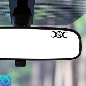 May include: A black and white car rearview mirror with a triple moon and pentacle symbol sticker. The sticker is centered on the mirror.
