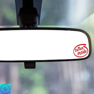 May include: A rearview mirror with a red sticker that says "Satan inside" in a white oval.