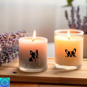 May include: Two lit candles with a dog graphic. One candle is a gradient of pink to gray, the other is yellow. Both candles have a black and white French Bulldog design. The candles are on a wooden tray.