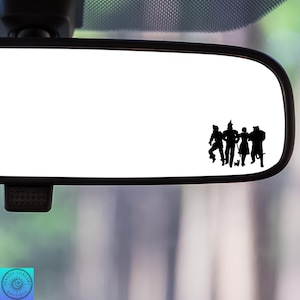 May include: A rearview mirror with a black silhouette of the Wizard of Oz characters, including Dorothy, the Scarecrow, the Tin Man, and the Cowardly Lion, walking together.