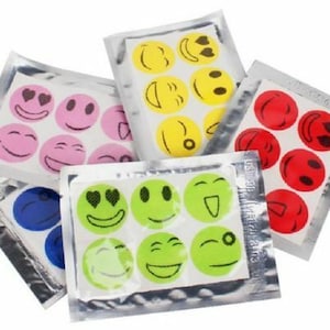 Puede incluir: Un paquete de parches repelentes de insectos coloridos con caras sonrientes. Los parches están diseñados para disuadir a los mosquitos y otros insectos.