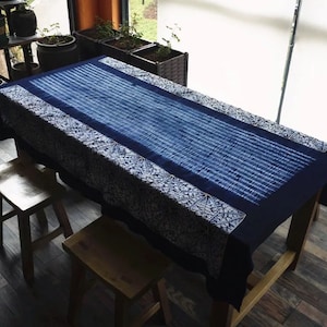 May include: A blue and white table runner with a geometric pattern. The runner is made of cotton and has a soft, textured feel. It is perfect for adding a touch of style to any table.
