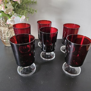 Peut inclure: Un ensemble de cinq verres assortis dotés de bols rouge foncé, de pieds en verre transparent et de bases circulaires. Les verres présentent une forme cylindrique lisse et sont disposés en groupe, mettant en valeur la couleur rouge vive du verre.