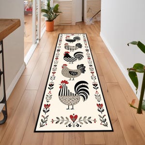 May include: A rectangular cream-colored runner rug featuring a repeating pattern of stylized roosters in black, gray, and white. The roosters are framed by a border of floral and heart motifs in red and black. The rug is placed on a wooden floor.