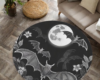 Könnte beinhalten: Ein runder schwarz-weißer Teppich mit einem Mond- und Fledermaus-Design. Der Mond ist voll und weiß mit einer grauen Oberfläche. Die Fledermäuse fliegen um den Mond herum und sind im Vintage-Stil gezeichnet. Der Teppich hat einen schwarzen Hintergrund mit weißen Details.