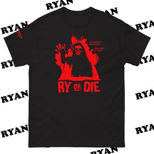 May include: Black t-shirt with a red graphic of a hooded figure with a skull face and outstretched hands. The text "RY OR DIE" is below the figure. Above the figure is the text "THEY WEREN'T NAMED RYAN NOW LOOK AT THEM".