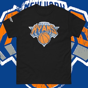 May include: A black short-sleeve t-shirt featuring a distressed graphic on the chest. The graphic displays the text NEW YORK RYANS in orange and white letters above an orange basketball, all set against a blue and white triangular background.