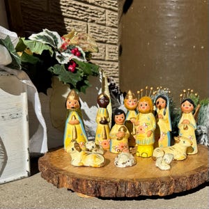 以下が含まれることがあります： 聖家族、三賢者、天使のフィギュアが特徴の手作りの降誕シーン。 フィギュアは黄色、青、茶色で塗装されており、木の輪切りに配置されています。 シーンには子羊と岩が含まれています。