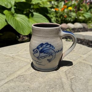 Caneca vintage de 1992 da ROWE Pottery Works, com esmalte salino cinza e desenho de peixe azul cobalto, fabricada em Wisconsin, EUA, com 11,4 cm de altura.