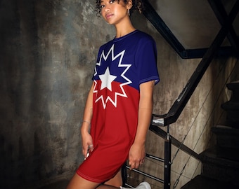 Könnte beinhalten: Kurzärmeliges Kleid mit auffälligem Design: blauer Oberteil, roter Unterteil und ein weißes Sternen- und Sternen-Emblem. Das Kleid wird mit weißen Turnschuhen getragen. Der Hintergrund ist eine Betonmauer und eine Treppe.