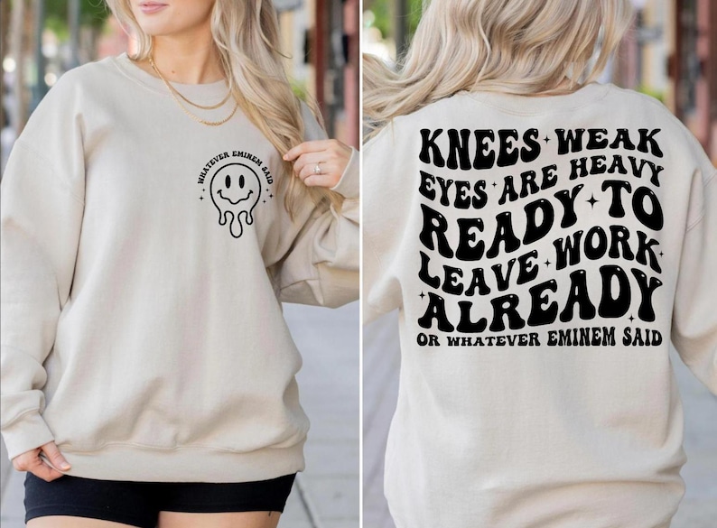 May include: Beige sweatshirt with a black smiley face graphic and the text "WHATEVER EMINEM SAID" on the front. The back features the text "KNEES WEAK EYES ARE HEAVY READY TO WORK LEAVE ALREADY OR WHATEVER EMINEM SAID" in black.
