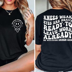 May include: Black t-shirt with a white graphic on the front of a melting smiley face and the text "WHATEVER EMINEM SAID". The back of the shirt has the text "KNEES WEAK EYES ARE HEAVY READY TO LEAVE WORK ALREADY OR WHATEVER EMINEM SAID".