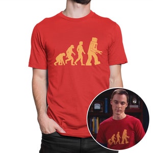 May include: Red t-shirt with a graphic of the evolution of man ending with a robot. The robot is holding a wrench. The text on the shirt says "The Evolution of Man".