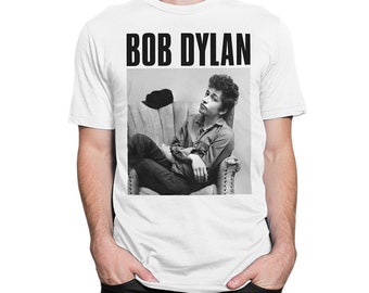 May include: White t-shirt with a black and white photo of Bob Dylan sitting in a chair. The text "BOB DYLAN" is printed in black letters above the photo.