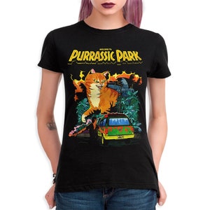 K&ouml;nnte beinhalten: Schwarzes Damen-T-Shirt mit einem Grafikdruck eines gro&szlig;en orangefarbenen Katers mit gr&uuml;nen Augen, einem gr&uuml;nen Van und dem Text "Willkommen im Purrassic Park".