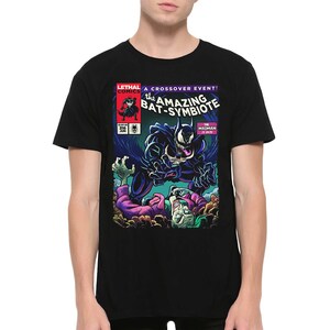 Könnte beinhalten: Schwarzes T-Shirt mit einem Comic-Cover-Motiv, das einen schwarzen und violetten Charakter mit dem Text "The Amazing Bat-Symbiote" und "A Crossover Event!" zeigt.