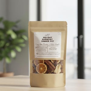 May include: A brown paper bag labeled "Holiday Harmony Simmer Pot" with a clear window showing dried orange slices, cinnamon sticks, and star anise. The text "Cozy Home Blessing & Festive Warmth" is also visible.