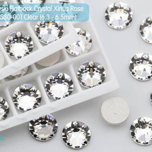 May include: Clear Swarovski flatback crystals, Xirius Rose cut, in a white tray. The crystals are 6.3-6.5mm in diameter. The image shows the crystals scattered and in a tray.