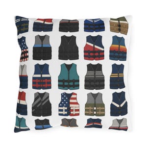 May include: A square throw cushion featuring a repeating pattern of various life jackets in different colours and designs, including solid black, blue, grey, and patterns like the American flag, stripes, and colour-blocked sections on a white background.