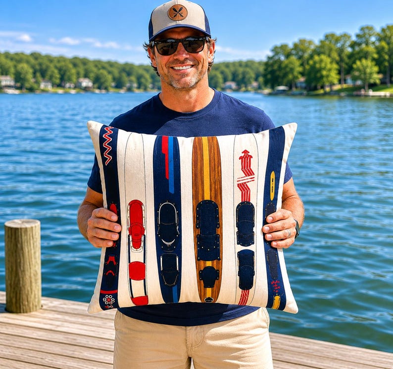 May include: A rectangular cushion with a design of water skis in red, blue, and brown. The skis are set against a cream background with vertical stripes. The cushion is held by a person wearing sunglasses and a baseball cap.