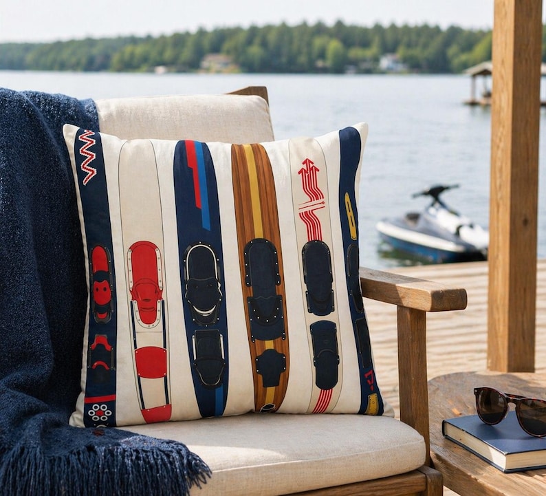 May include: Cushion with a cream background featuring a pattern of water skis in various colours, including red, blue, and brown. The cushion is on a wooden chair with a lake and trees in the background.
