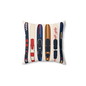 May include: Square pillow featuring a pattern of vintage water skis in various colors. The skis have red, blue, and white accents, with black bindings. The pillow has a cream-colored background.