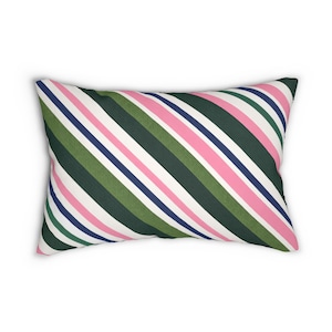 May include: Rectangular pillow with a diagonal striped pattern. The stripes alternate between white, pink, dark green, navy blue, and light green. The pillow is a decorative item for a bed or sofa.