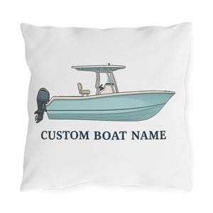 May include: White pillow with a light blue boat illustration. The boat has a white frame, a black motor, and the text "CUSTOM BOAT NAME" in navy blue. The pillow is square.