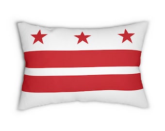 Könnte beinhalten: Ein rechteckiges Dekokissen mit der Flagge von Washington, D.C. Das Design besteht aus einem weißen Hintergrund mit zwei horizontalen roten Streifen und drei roten fünfzackigen Sternen, die in einer Reihe im oberen Bereich angeordnet sind.