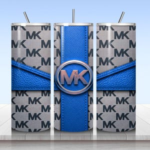 May include: A cylindrical tumbler with a straw featuring a gray and black repeating MK logo pattern. A bright blue textured band wraps horizontally around the center, intersected by a vertical blue stripe with a circular MK logo emblem in the middle.