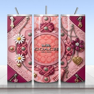 May include: A cylindrical tumbler with a straw featuring a pink and magenta leather-textured pattern with Coach New York branding. The design includes metallic chains, daisy flowers, heart charms, zippers, and intricate lace-like cutouts in shades of pink.