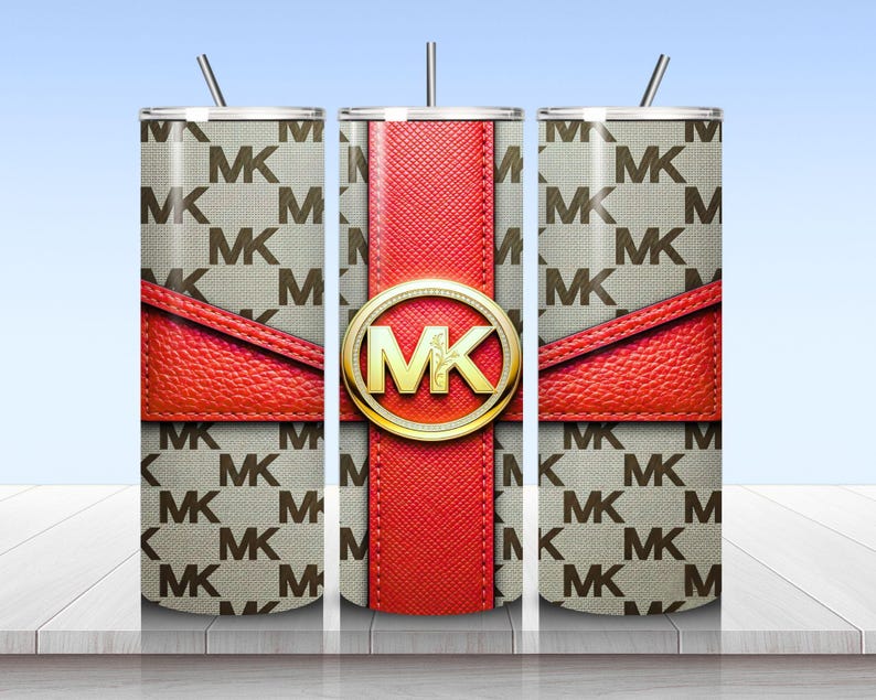 May include: A cylindrical tumbler with a straw featuring a beige and brown repeating MK logo pattern. A textured red band wraps horizontally around the center, intersected by a vertical red stripe and a gold circular emblem with the letters MK.