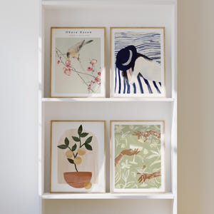 Könnte beinhalten: Vier gerahmte Kunstdrucke, die auf einem weißen Regal ausgestellt sind. Die Drucke zeigen botanische und figurative Illustrationen. Ein Druck zeigt einen Vogel auf einem blühenden Zweig, ein anderer eine Person mit Hut und zwei weitere Pflanzen und Cocktails.